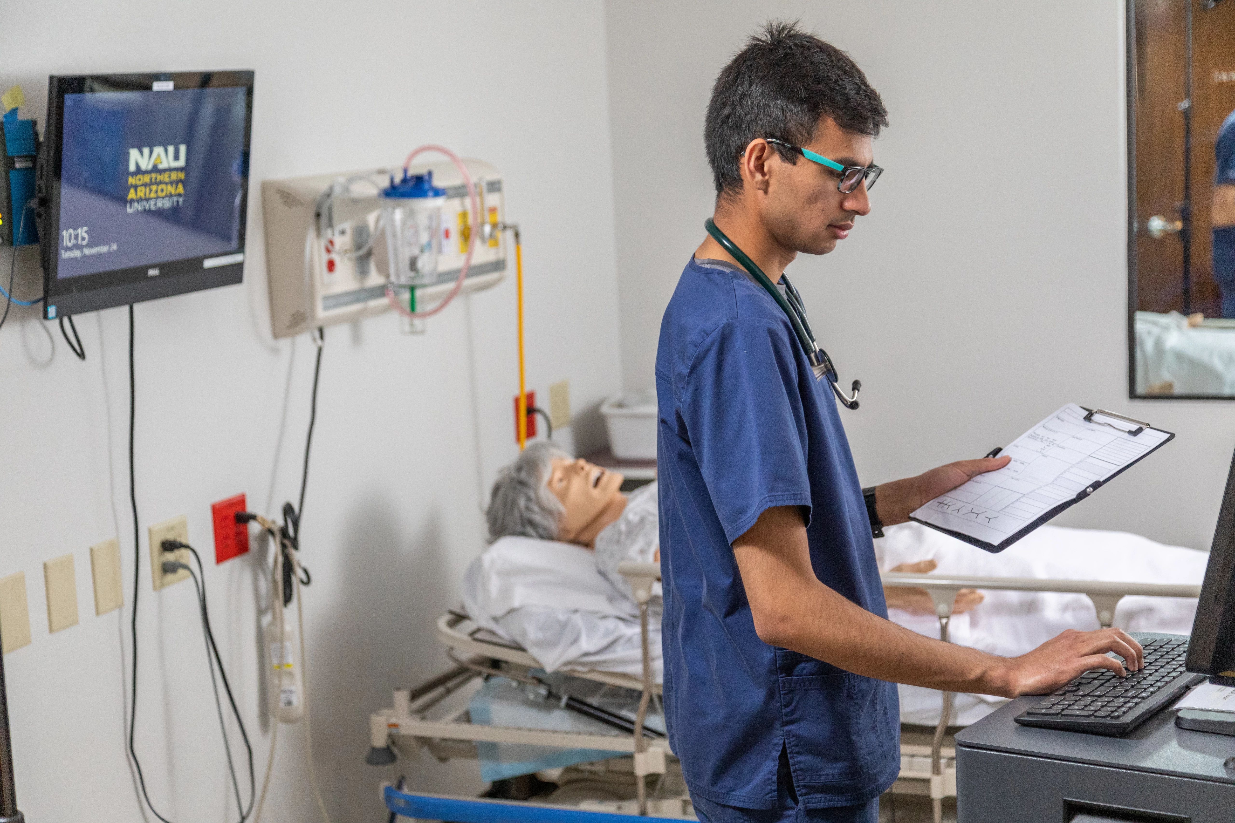 Nursing student putting patient vital information into computer.