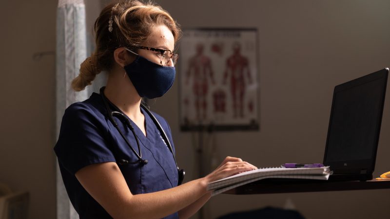 Nursing student typing on laptop.