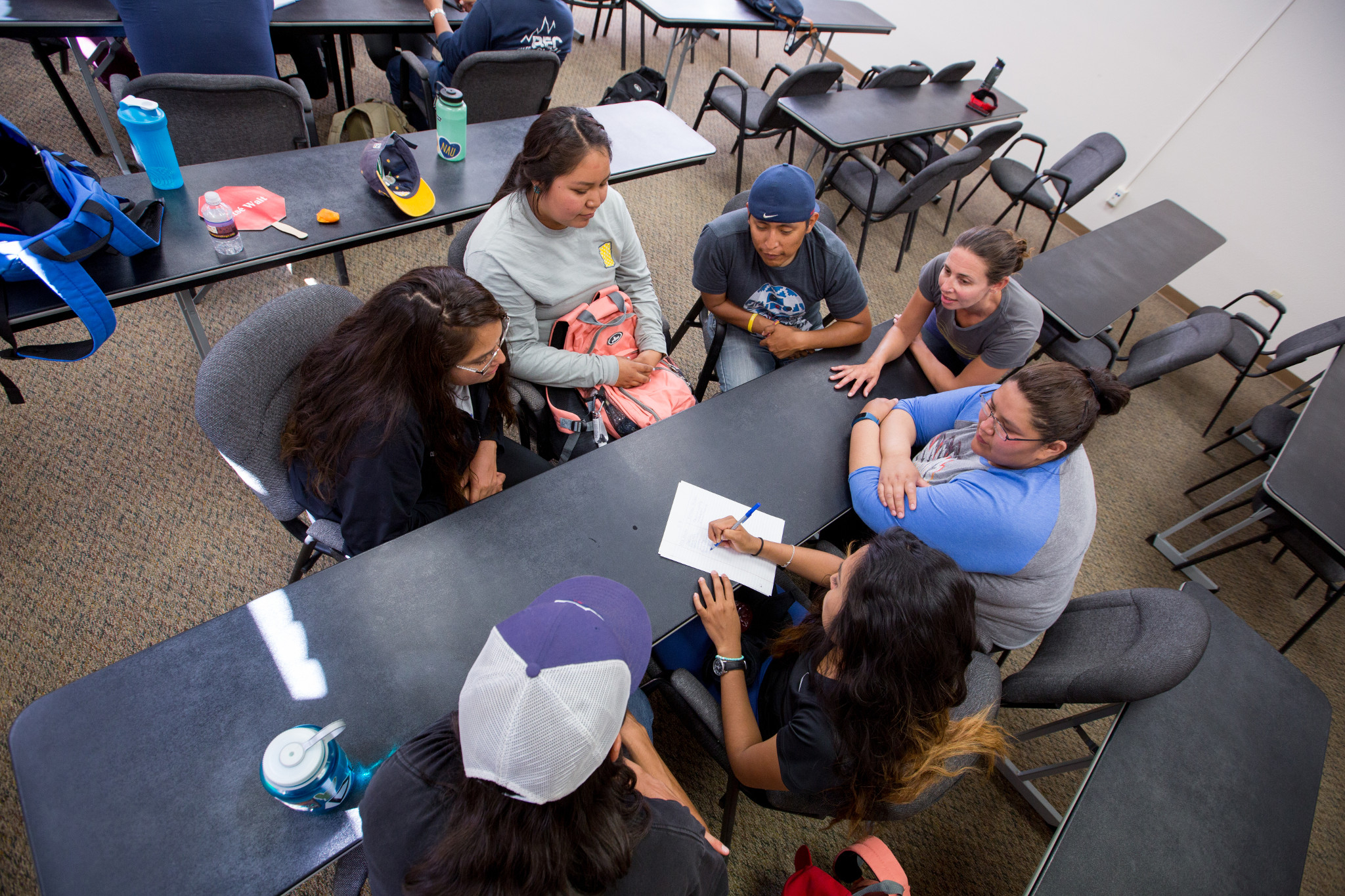 Students chatting around a table in a classroom.