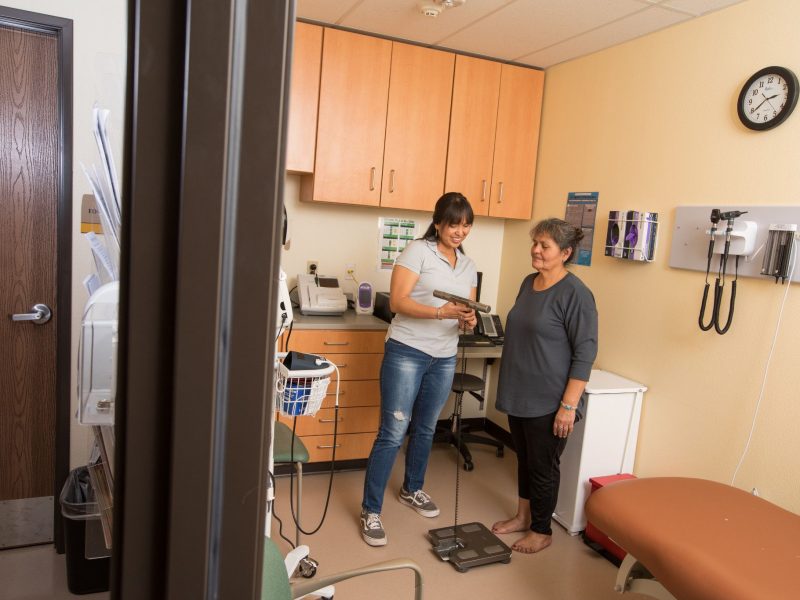 Woman getting weighed at medical facility.