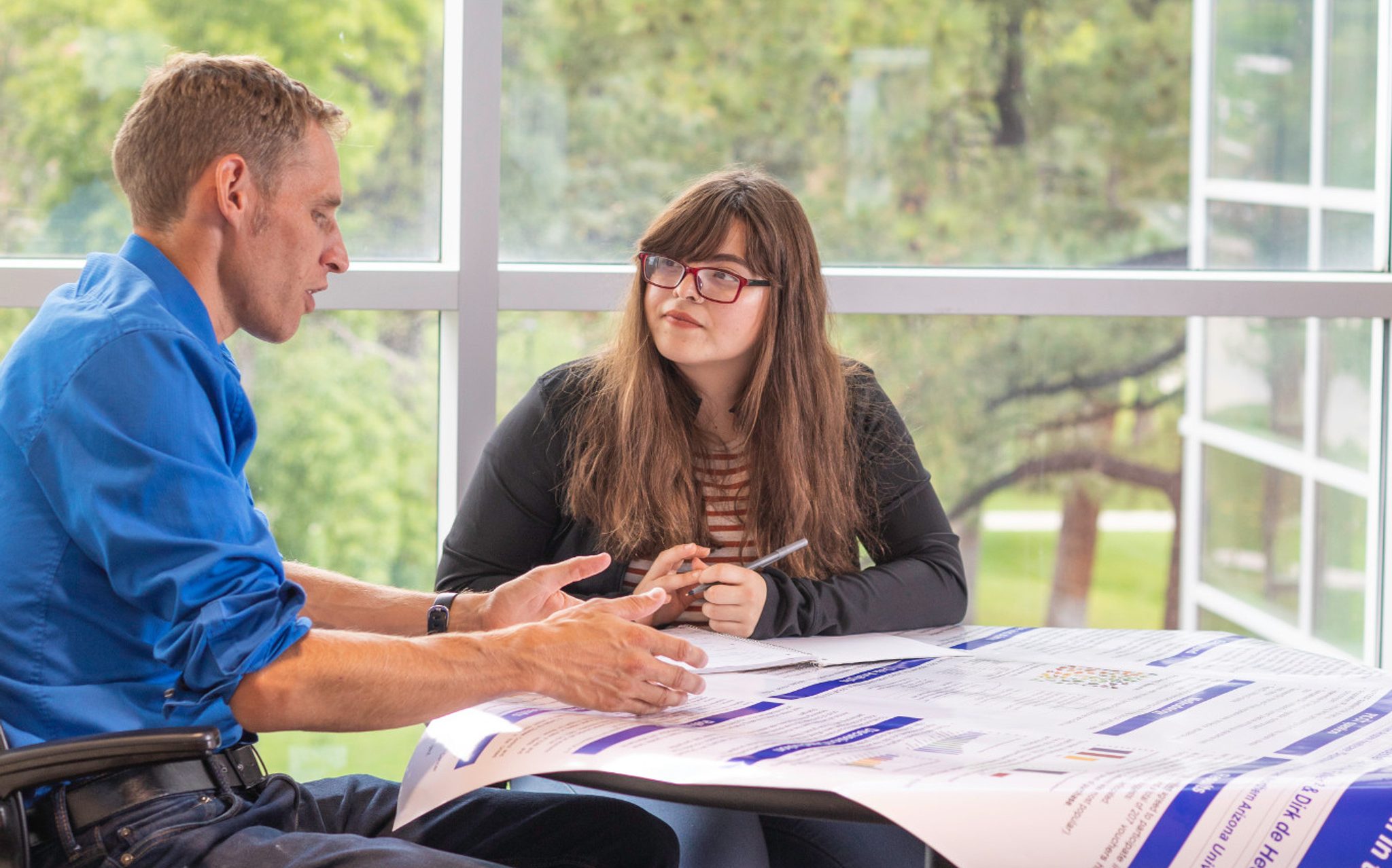 Dirk de Heer talking to a student abou their research poster.