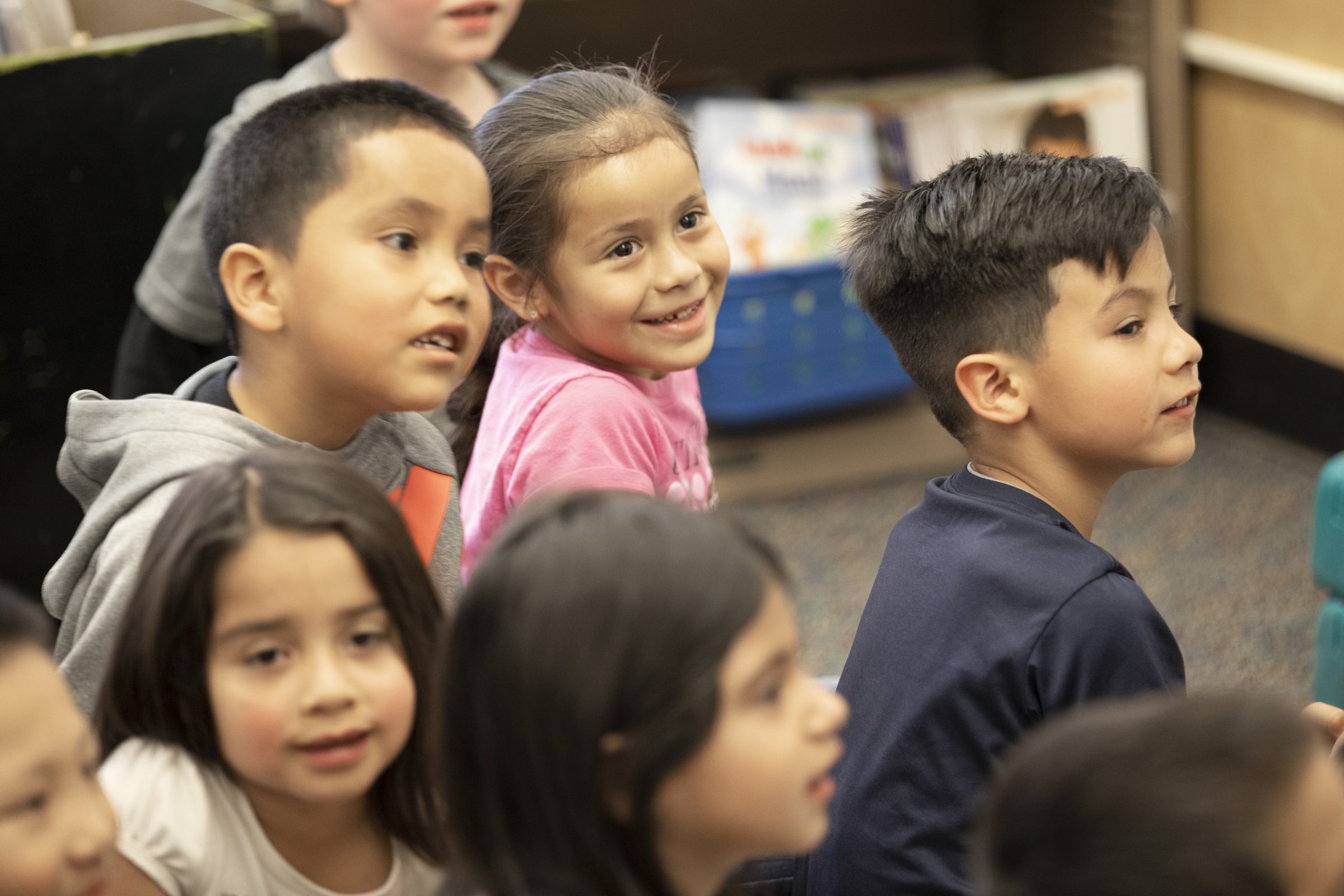A group of young children sitting on the floor listening