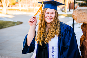 Bethany Robinson poses in her graduation attire outside.