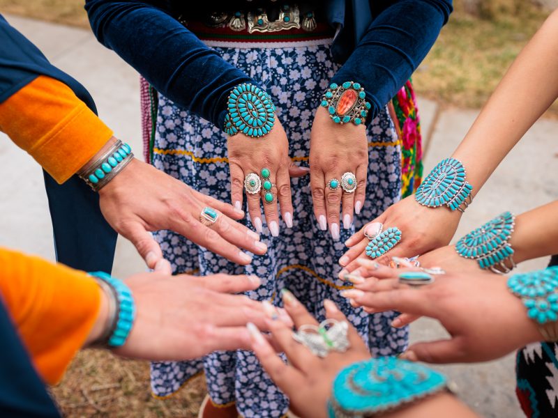 Hands wearing turquoise jewelry, making a circle with their hands