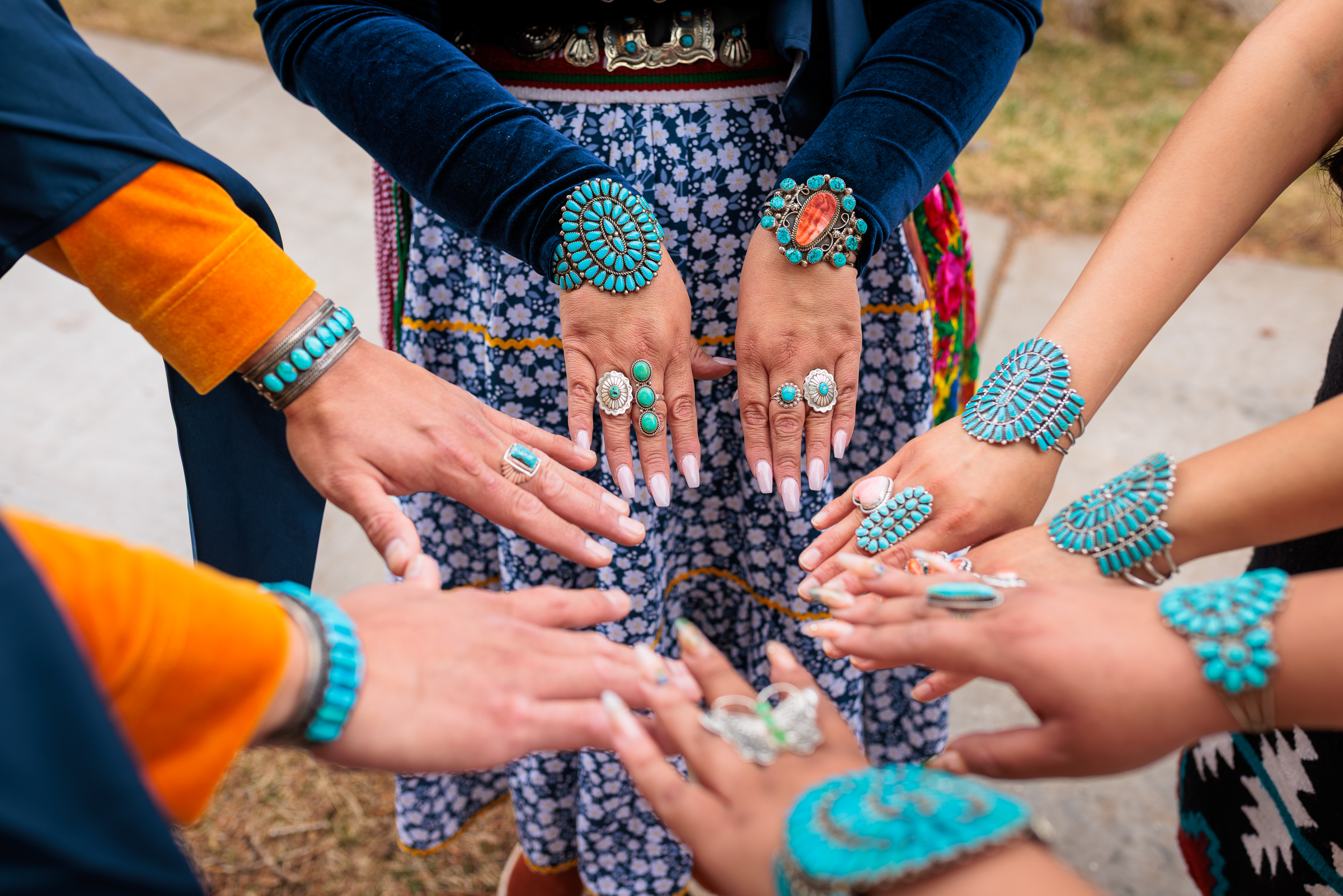 Hands wearing turquoise jewelry, making a circle with their hands
