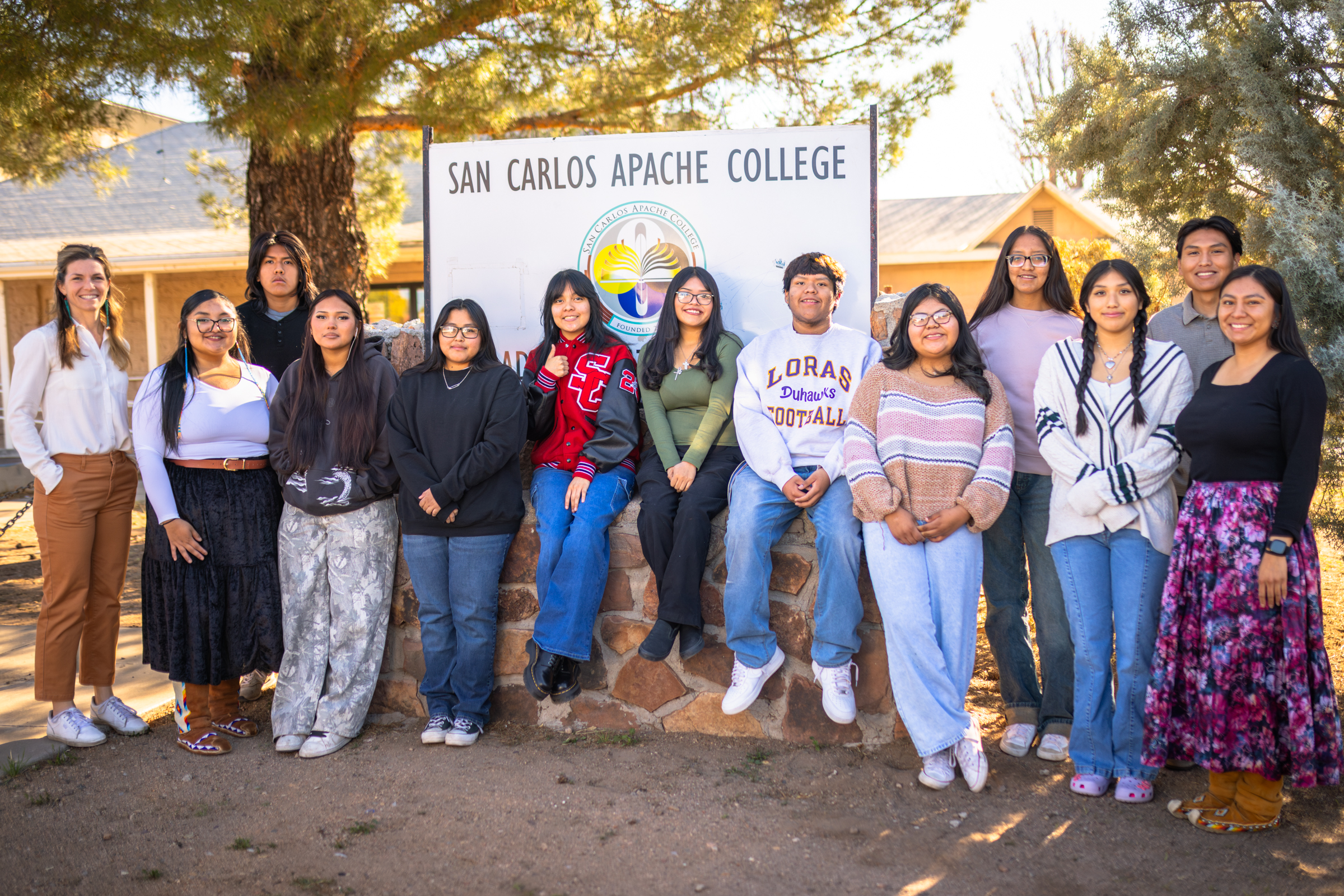 A group of students outside lined up in front of the San Carlos Apache College sign.