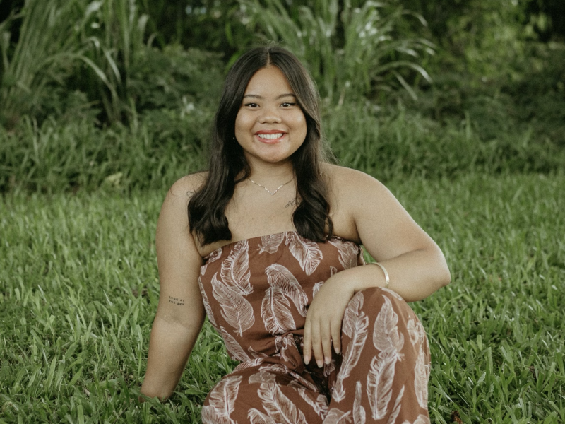 Taylor Langaman sitting on grassy field.