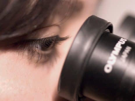 student looking through the lens of a microscope