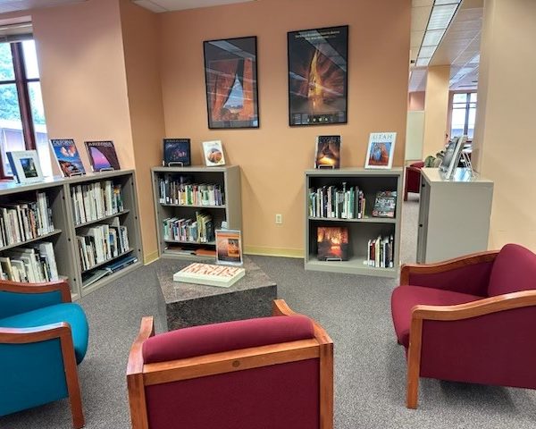 Bookshelves holding the David Muench Research Library with a few seats and a table.