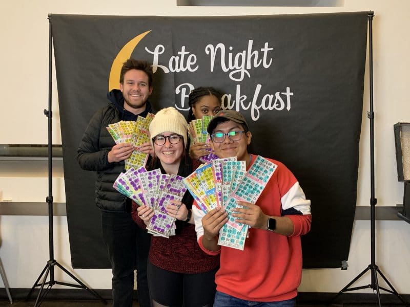 A picture in front of the late night breakfast sign with bingo sheets