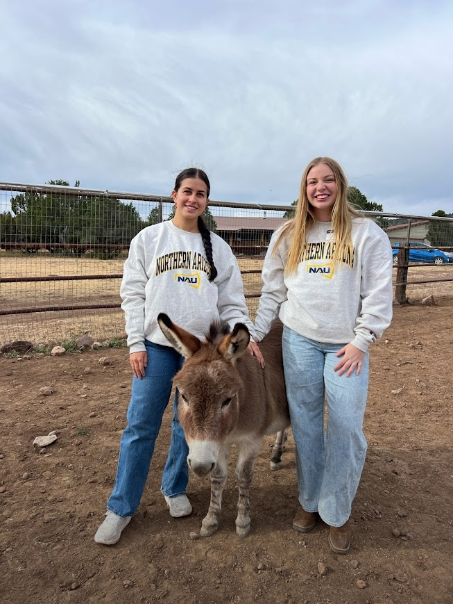 Two students posing with a small donkey.