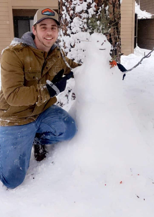 Man standing next to a snowman
