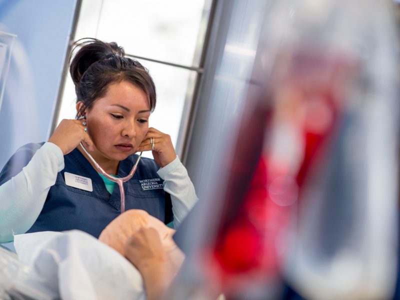 Doctor holding stethoscope in her ears.