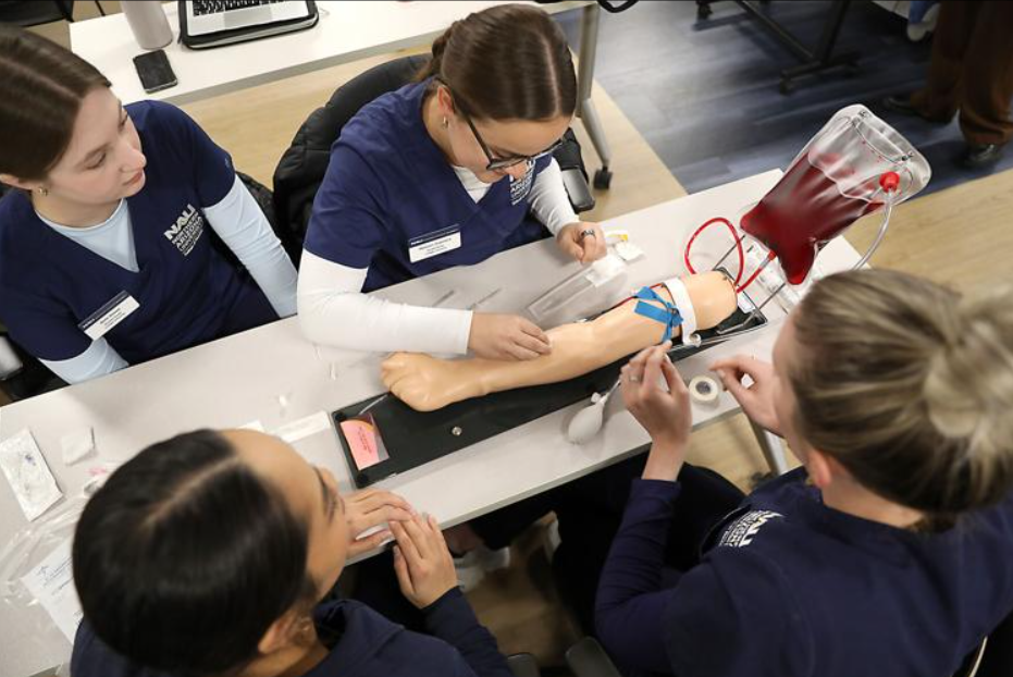 Nursing students practicing placing IVs into a practice arm.