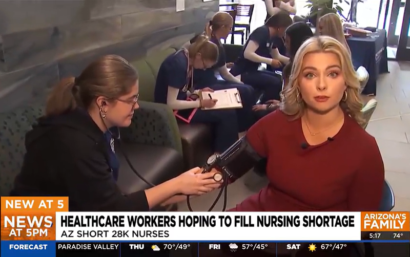News image of news anchor getting her blood pressure checked by a NAU nursing student.