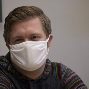 A masked student sits in a conference room during a coaching session. 