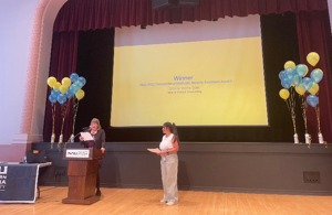 Giselle receives her award at a podium with NAU Graduate College