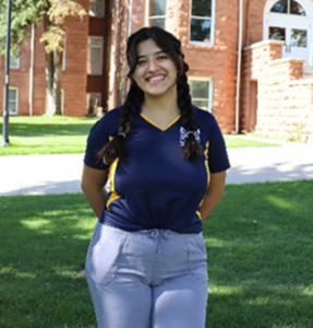 Giselle standing outside in a grassy area smiling at camera