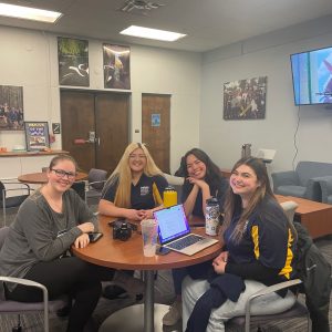 Four Transfer Jacks Mentors sitting around a table, smiling at the camera in the Transfer Lounge.