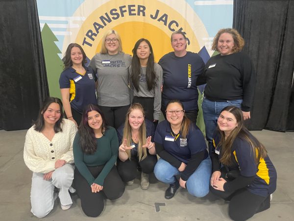 Transfer Jacks Team smiling at camera, a Transfer Jacks photo backdrop is behind them.