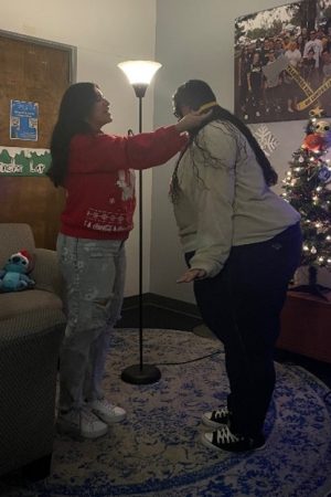 Giselle Soto putting a graduation medallion on Yendira Pineda's neck.
