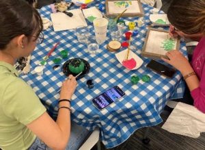 Students painting canvases at table