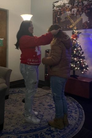 Giselle Soto putting a graduation medallion on Brynn Merz's neck.