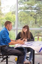 Dirk de Heer works with a student on a poster presentation.