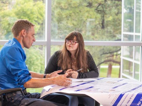 Dirk de Heer works with a student on a poster presentation.