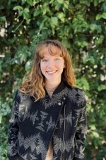 A woman with red hair against a green, grassy background