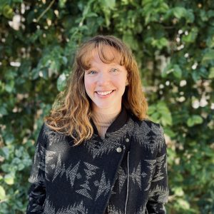 A woman with red hair against a green, grassy background