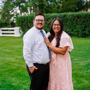 Brighten stands next to her husband in a grassy area.