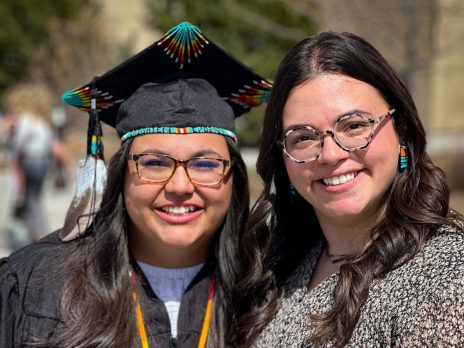 Two women pose for a photo during a graduation ceremony.