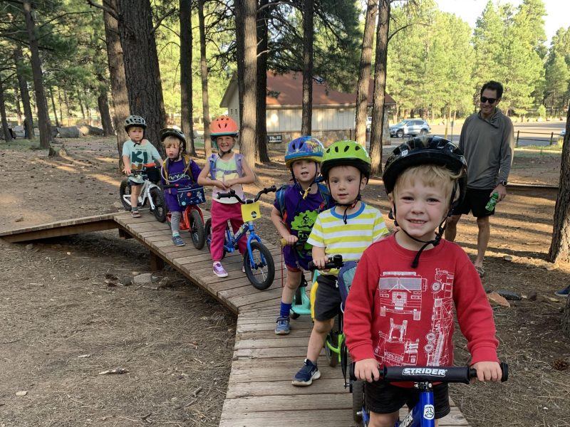 A group of FLYERS mountain biking kids riding on a wooden path.