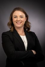 A woman posing in a black dress coat