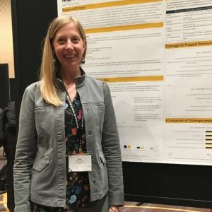 Kelly poses with her research poster at a conference.