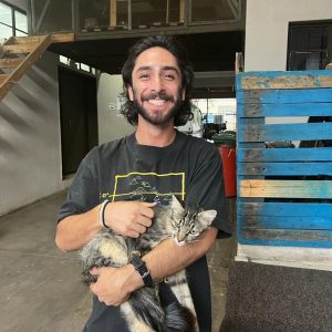Nick Calles holds a cat and smiles.