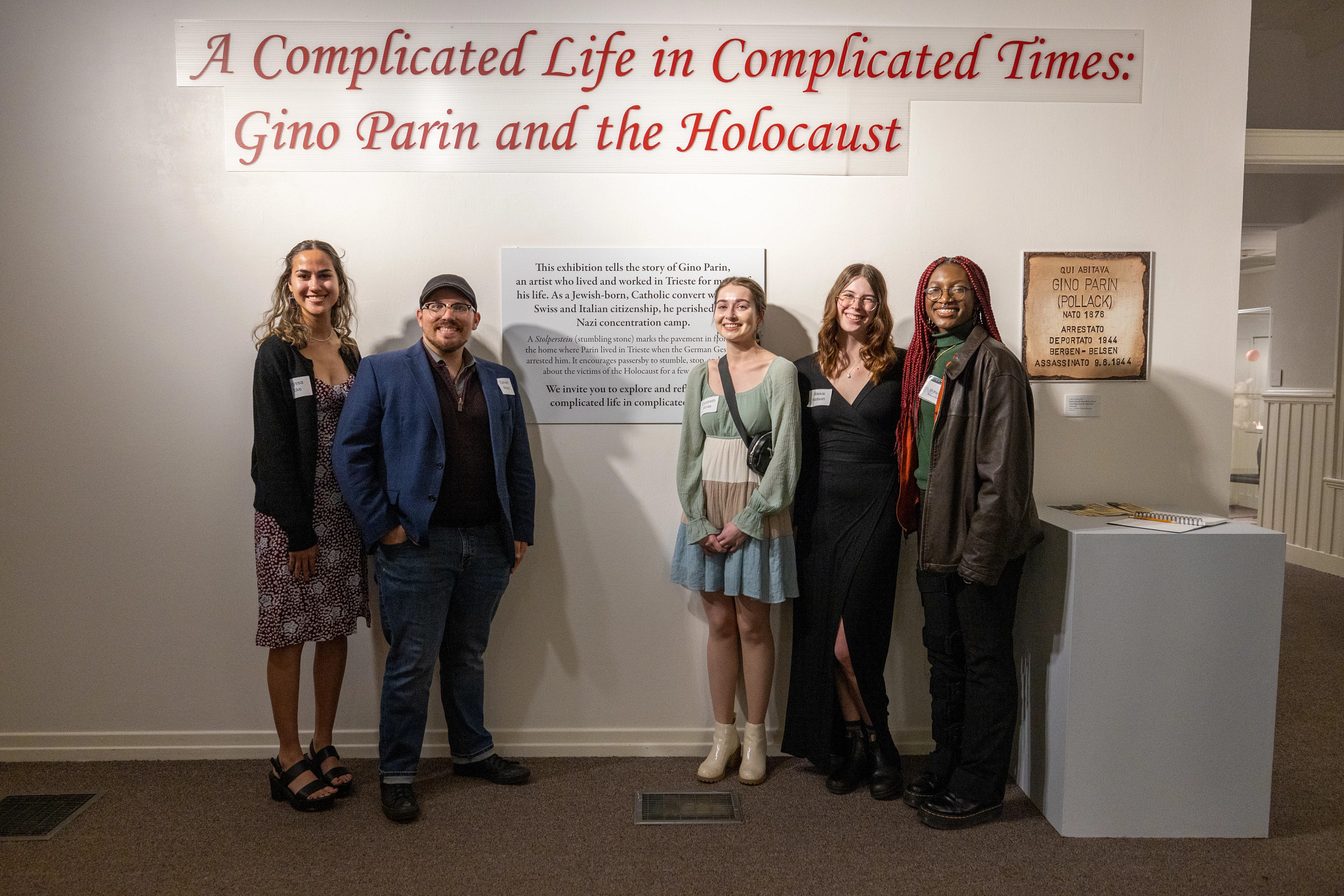 Five interns stand in front of text poster at Gino Parin exhibit