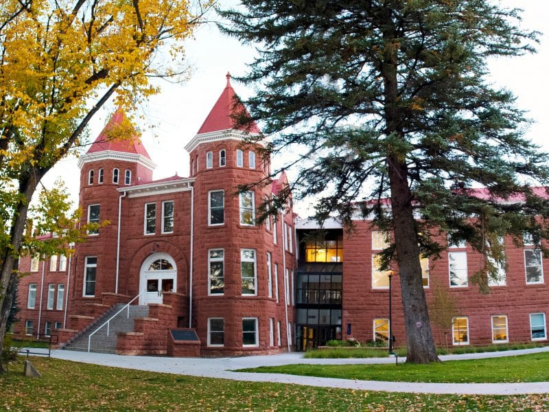 Front of NAU's Old Main surrounded by trees and grass