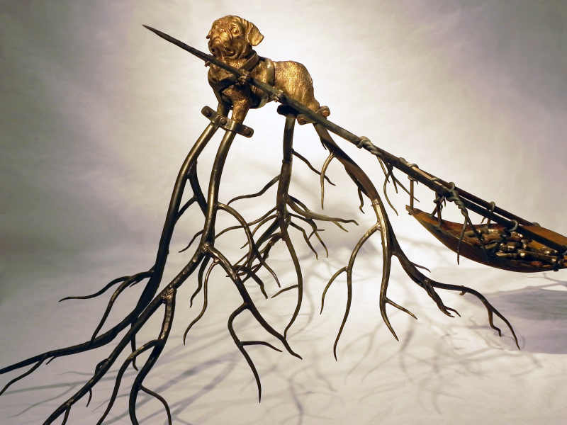 Sculpture of Dog whose legs become leafless tree branches, pulling a sled full of milkbones.