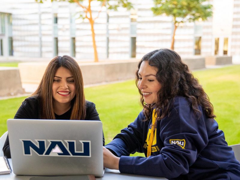 N A U–Yuma students outside working on Laptop.