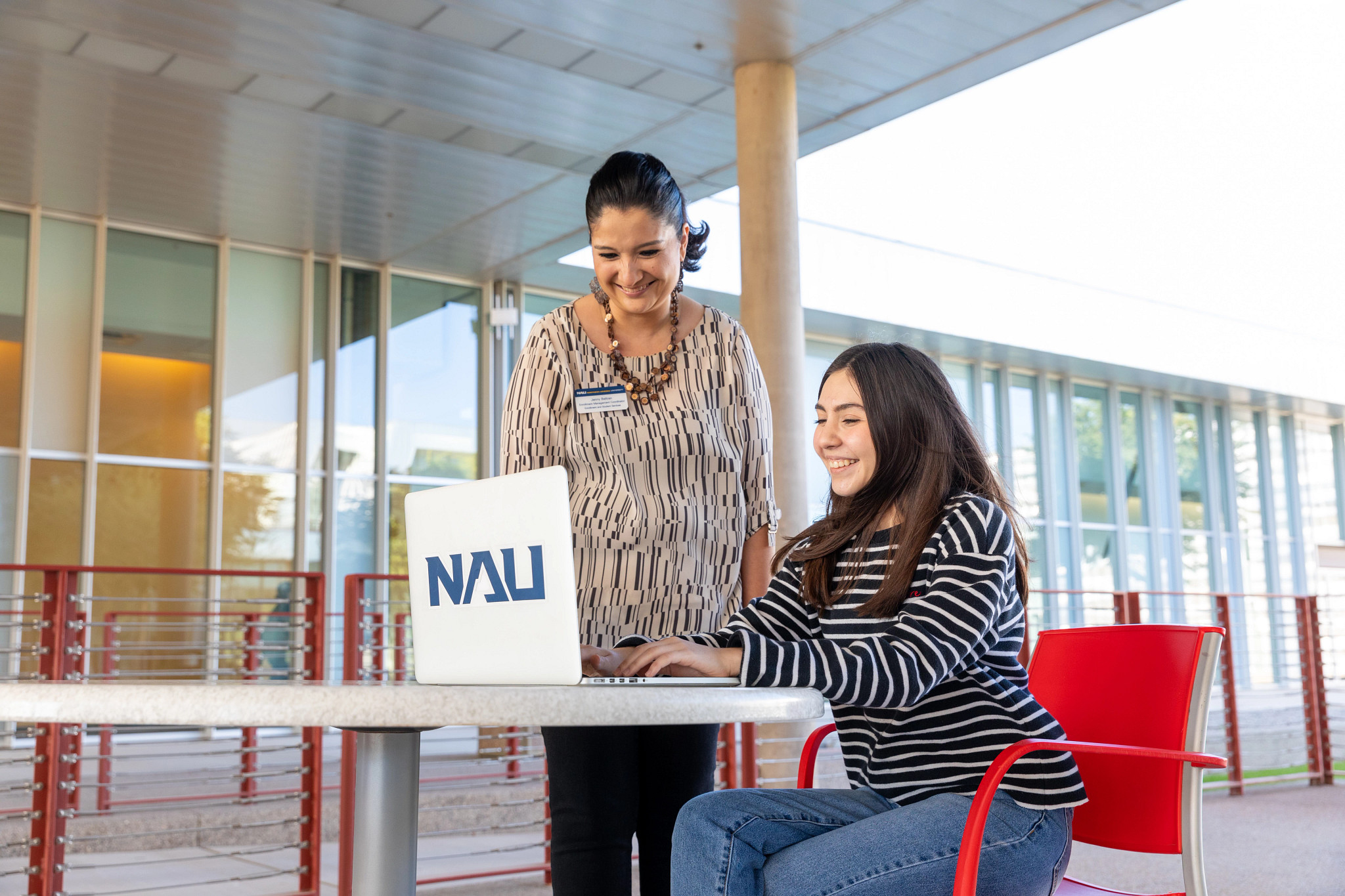 N A U–Yuma advisor works with a student on their laptop outside.