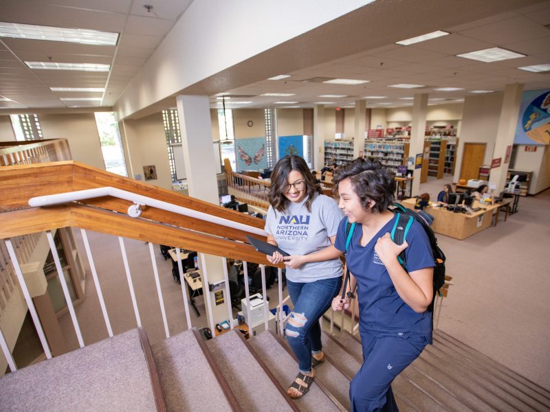 N A U–Yuma students walking in library.