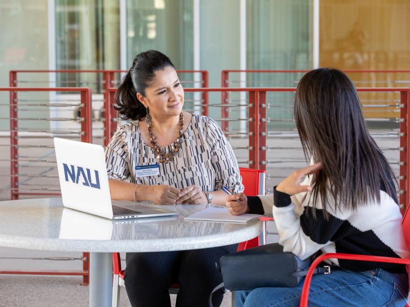 An N A U–Yuma advisor working with a student outside.