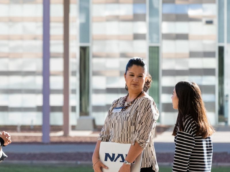 Students talking with an advisor outside at the N A U–Yuma campus.